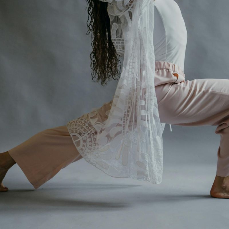 Person in a focused yoga pose against a dark, dramatic background.
